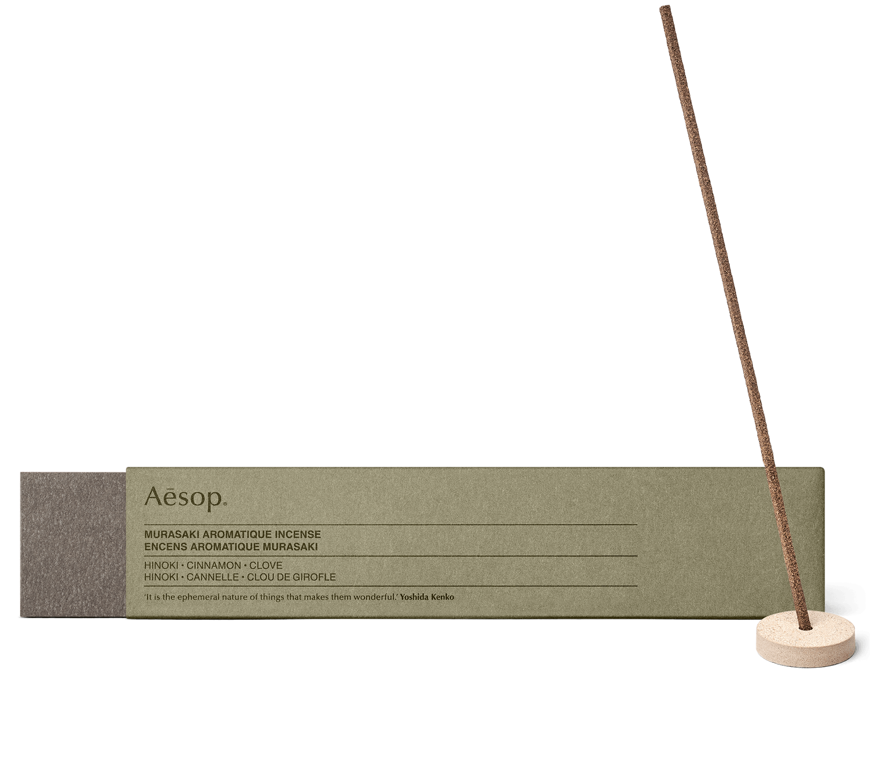Un bâtonnet d’Encens Aromatique Murasaki dans le support en pierre ponce Kanuma, à côté de l'emballage en carton.