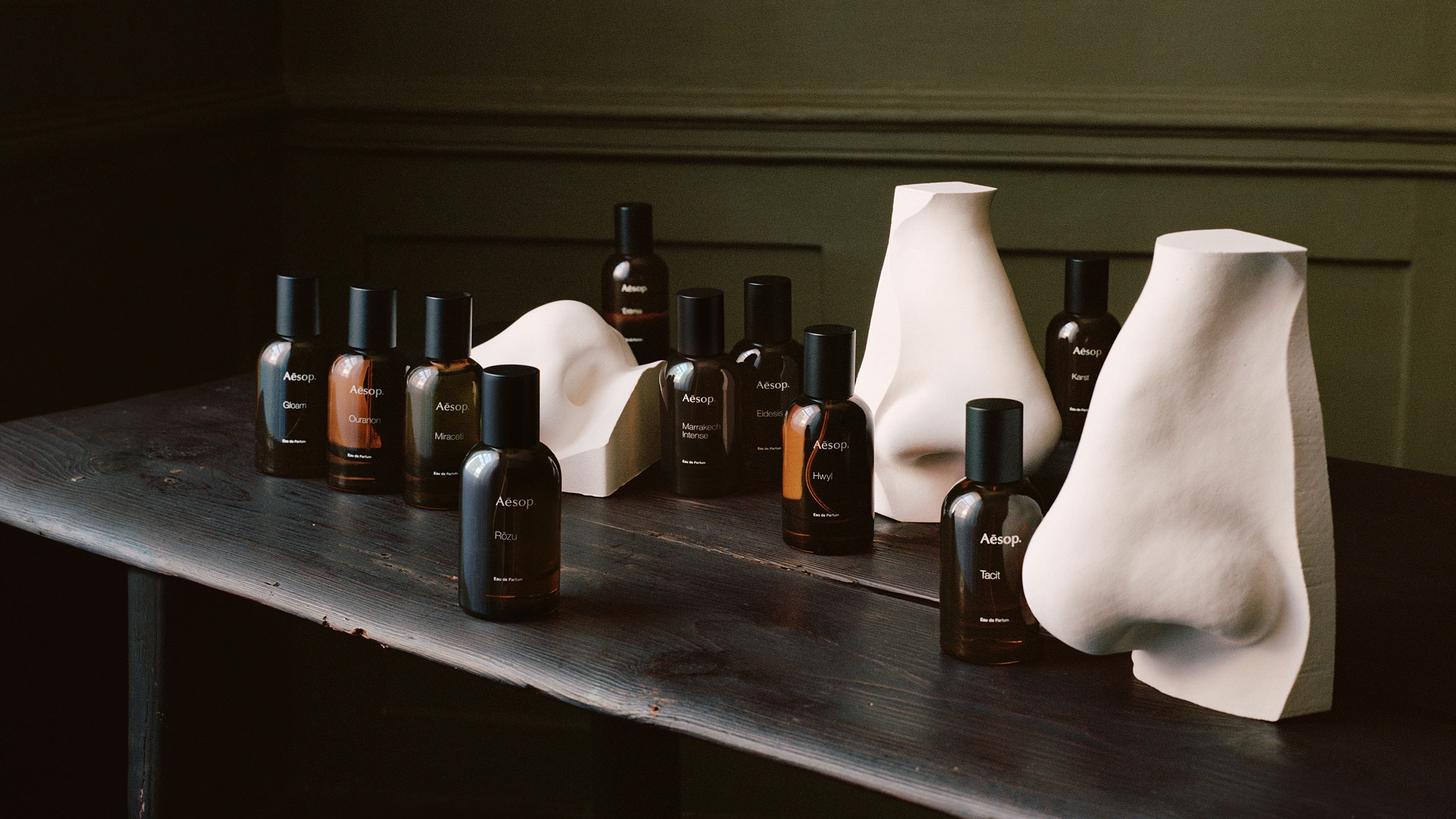 Aesop fragrances in amber bottles placed next to nose sculptures