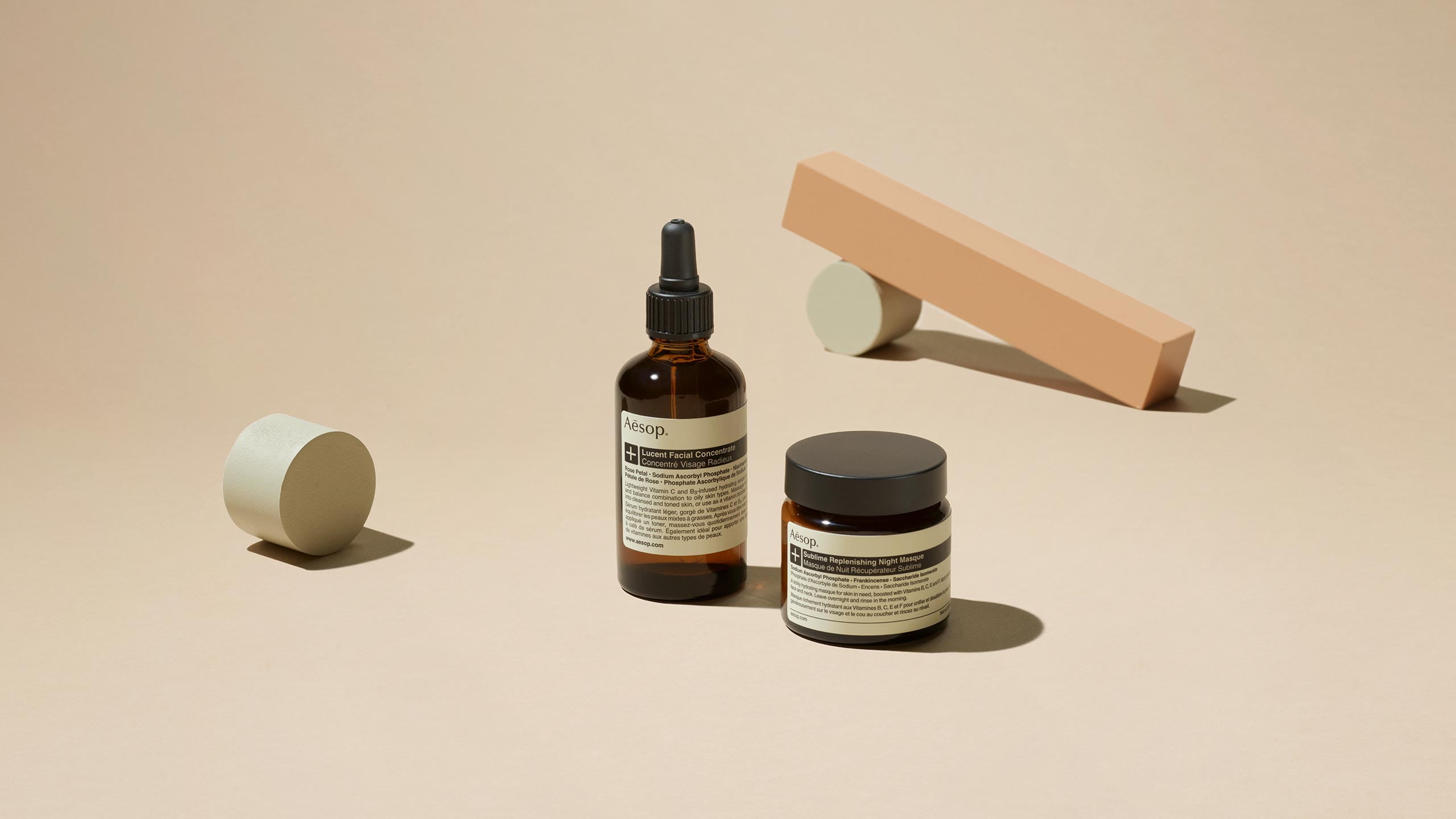 Lucent Facial Concentrate and Sublime Replenishing Night Masque in front of geometric blocks
