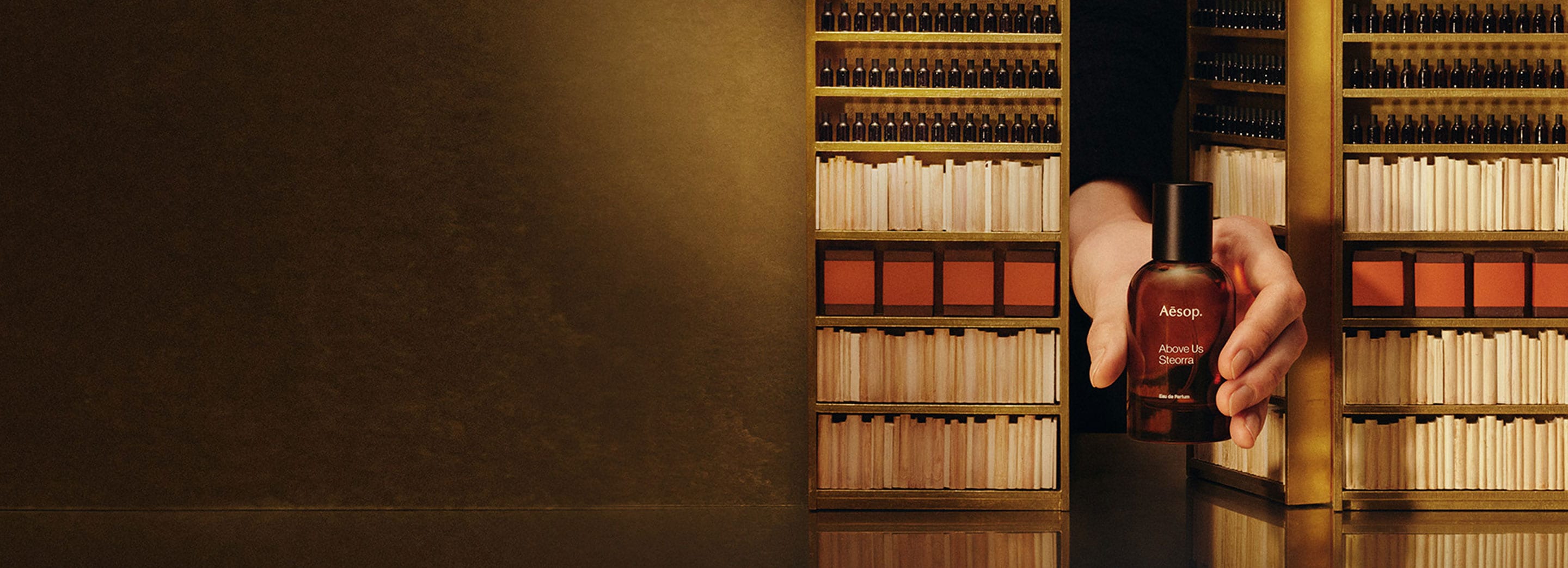 A hand holding an Aesop fragrance through a mini door
